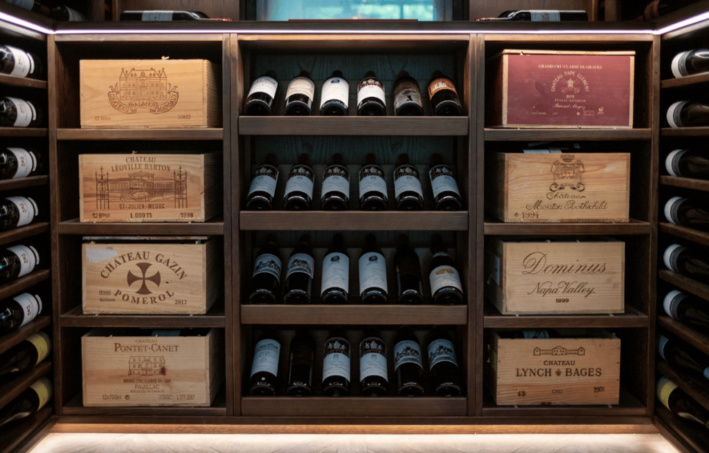 The lower level of a Dark Oak wine wall. Angled wine bottles sit centrally with draws for old wine cases either side.